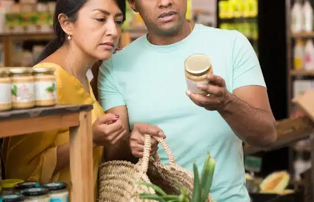 two people in a supermarket looking at the label on a food item