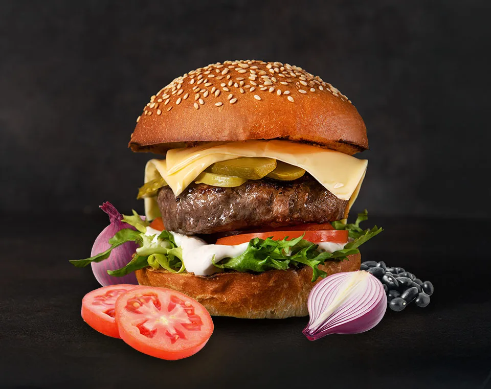 Plant based burger with ingredients on black, black beans, tomatos, onions