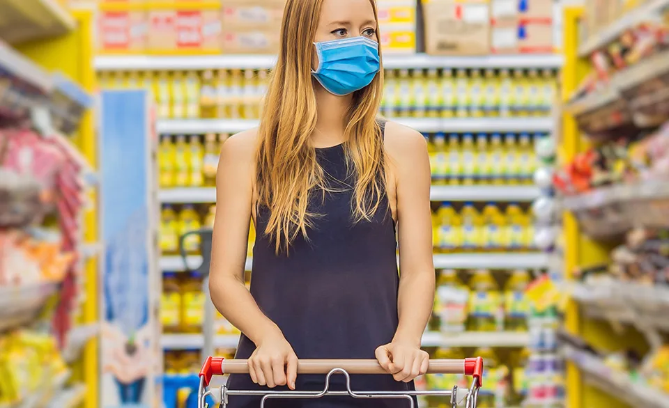 woman in mask grocery shopping post covid-19